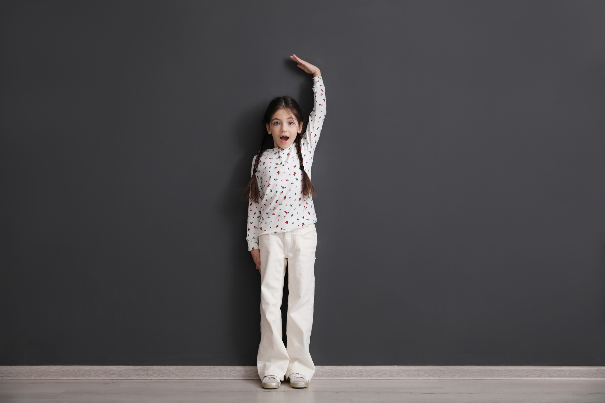 Emotional Little Child Measuring Her Height near Black Wall Indo